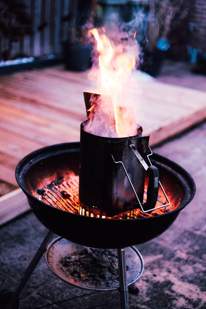 The Art of Drawing Readers In: Your attractive post title goes here Close-up of a charcoal grill with flames and chimney starter outdoors.