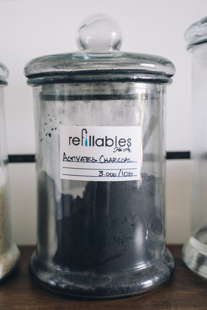 Close-up of refillable activated charcoal in a labeled glass jar for eco-friendly use.