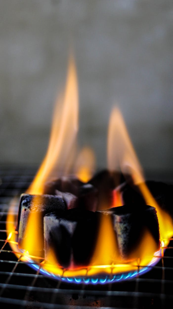 Mastering the First Impression: Your intriguing post title goes here Burning charcoal cubes on a grill with vibrant flames in vertical orientation.